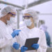 Product researcher or quality control engineer or production line worker in white sterile uniforms prevent contamination of food and drink product industry or cosmetic manufacturing plants or processed food or canned food, discuss about product at factory